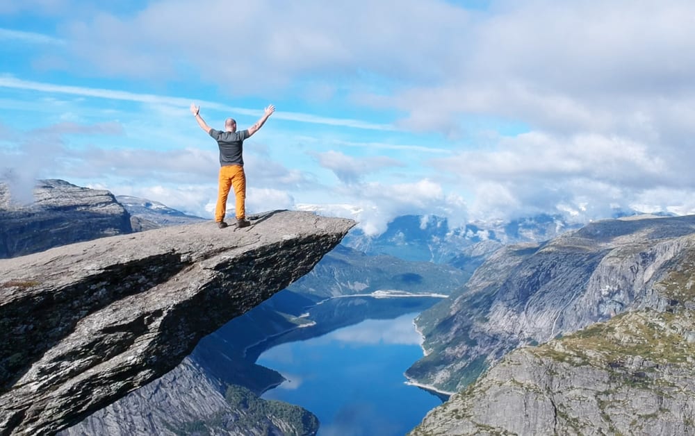 Carl with arms raised on Trolltunga, above the Norwegian fjords